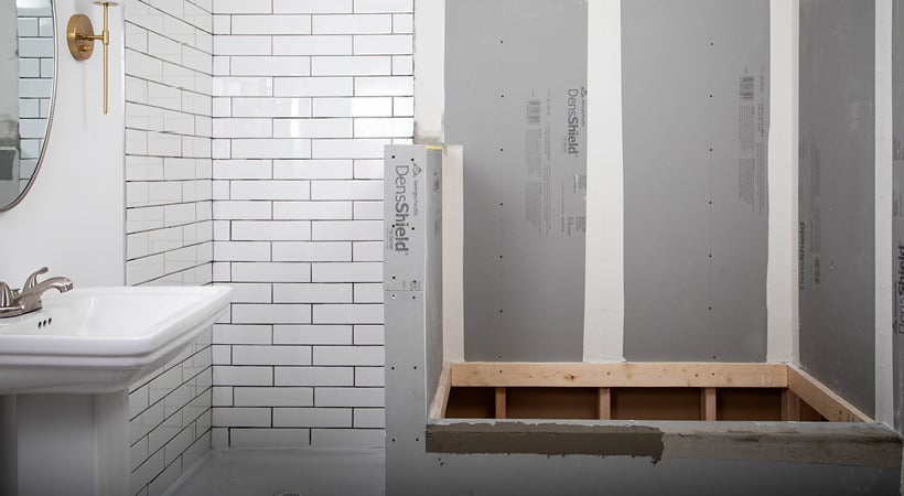 A partially tiled white bathroom shows DensShield® Tile Backer installed in the tub area.